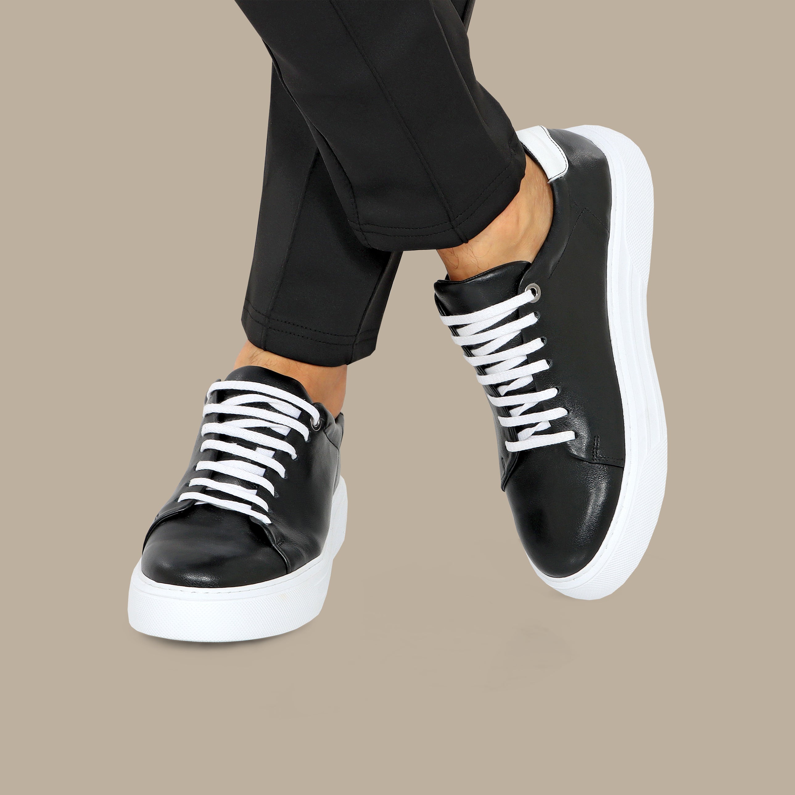 Black low-top leather sneakers with white laces and contrasting white heel tab on white sole.