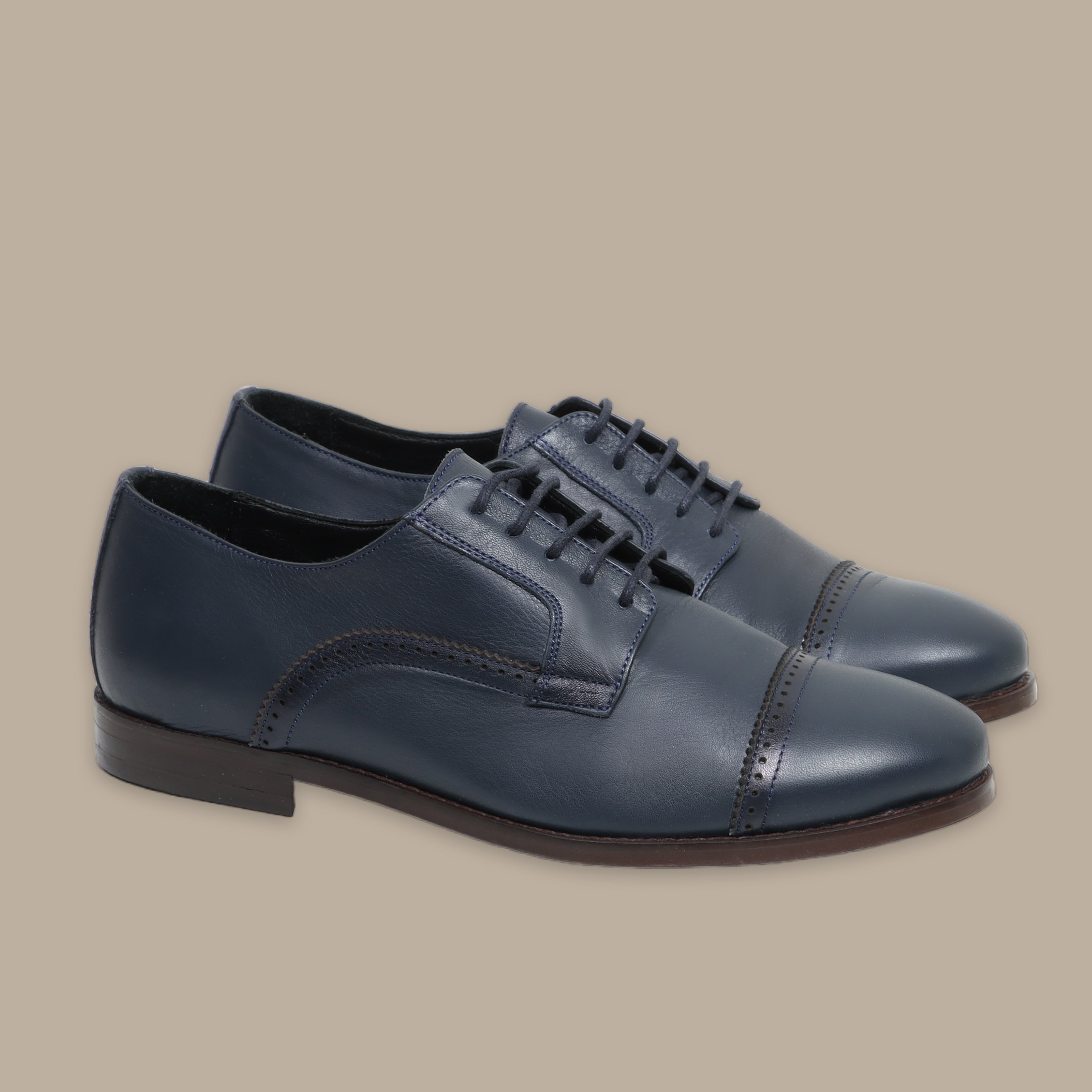 Navy leather oxford shoes with cap toe and closed lacing on beige background.