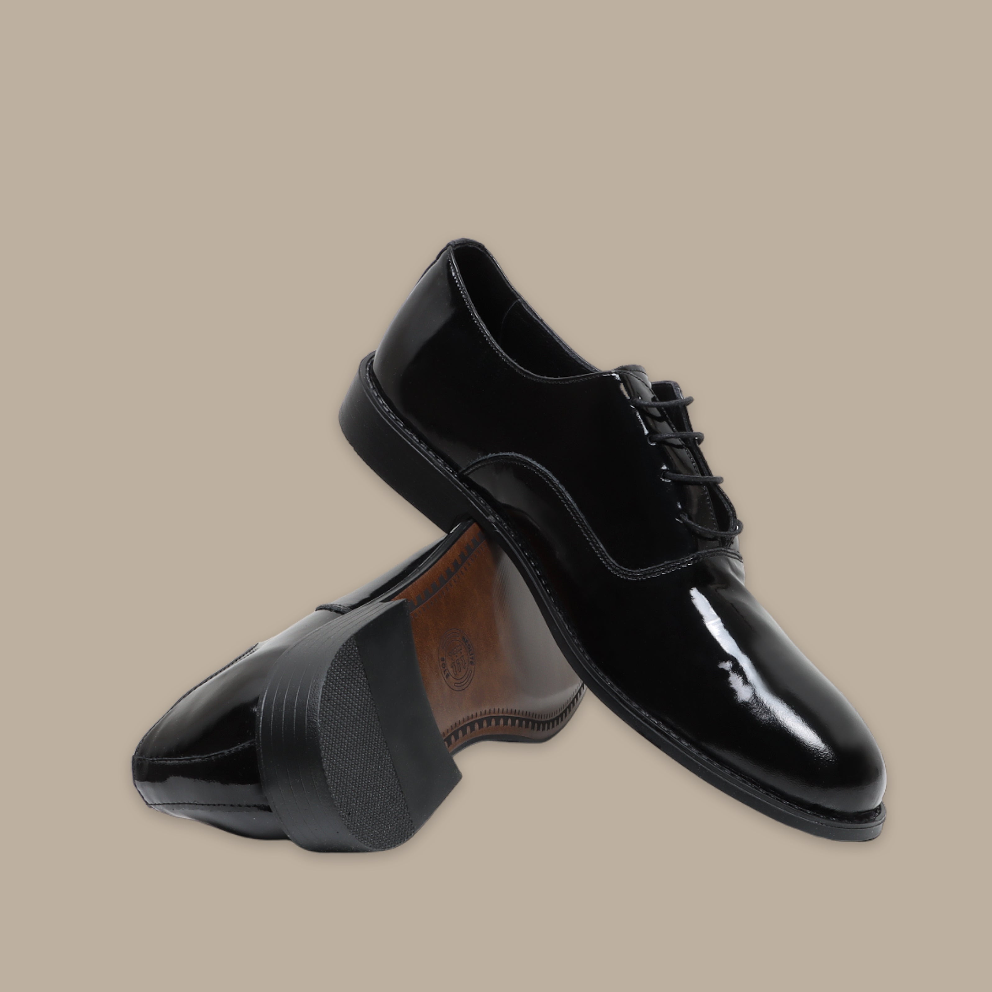 Black tuxedo shoes with glossy patent leather finish and lace-up design on beige background.