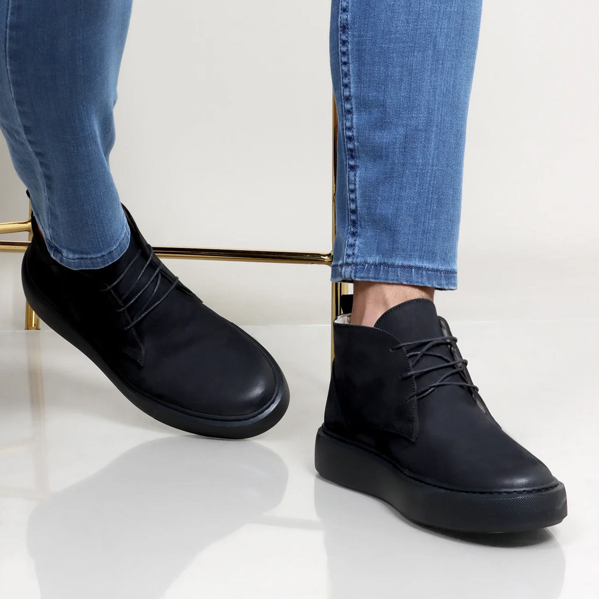 Black nubuck half boots with round toes and lace-up fronts worn with blue jeans.