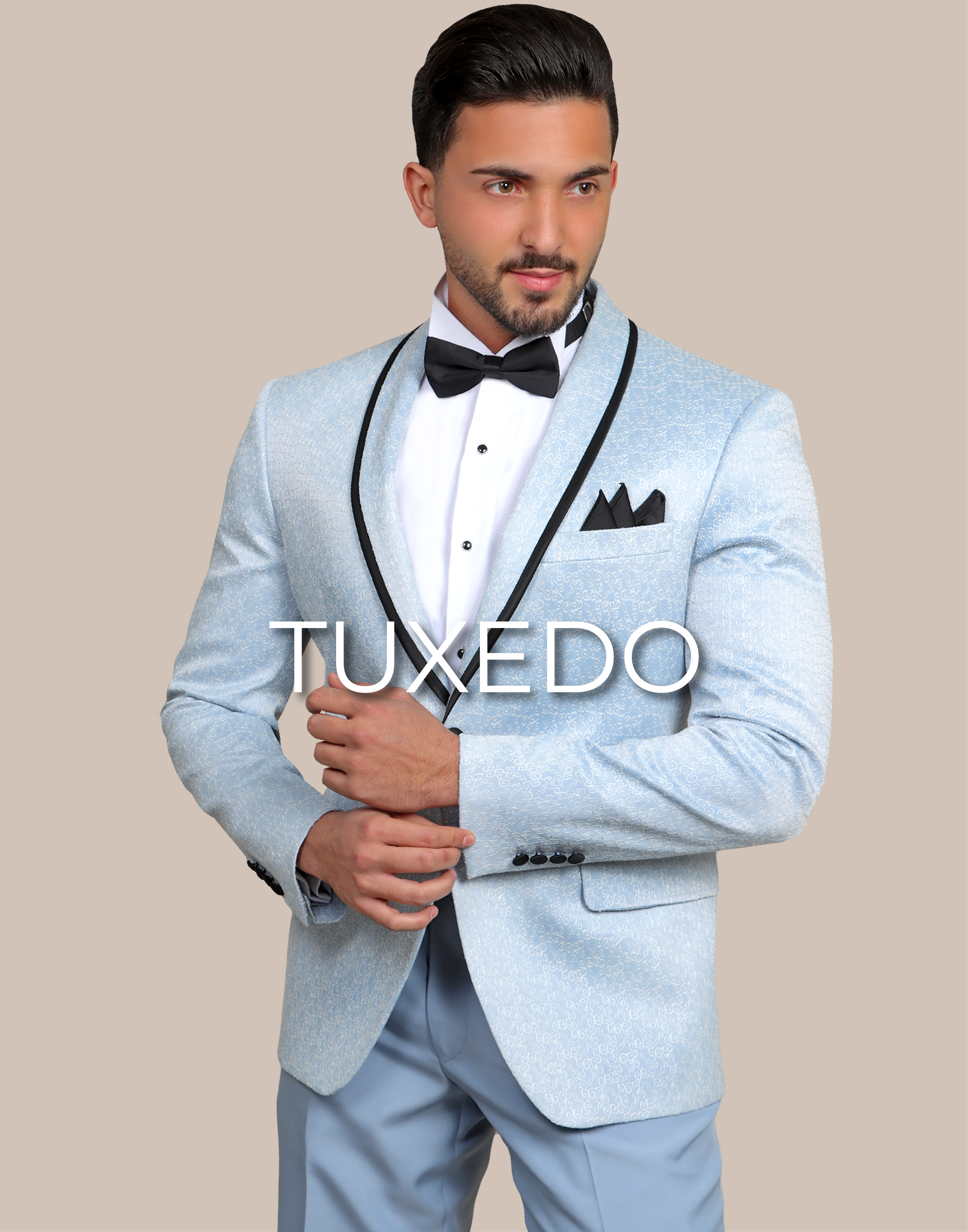 A standing model is wearing a light blue tuxedo and he's hands above each others and is written on the image tuxedo